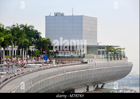 Infinity Pool auf der Dachterrasse an der Marina Bay Sands Skypark, in Singapur, die Menschen entspannend auf die atemberaubende Aussicht. Stockfoto