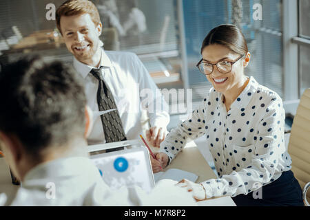 Upbeat Büroangestellte lächelnd, während ihre Kollegen sprechen Stockfoto