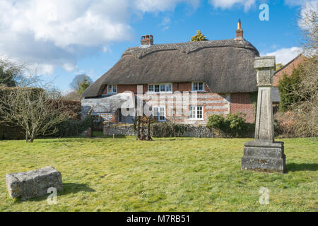 Charmantes strohgedecktes Cottage und Village Green in Martin Dorf in Hampshire, Großbritannien, mit der Replica 2000 Dorf Kreuz Stockfoto