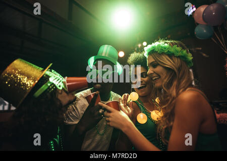 Gruppe von multi-ethnischen Freunden Spaß an der Bar. Lächelnde Männer und Frauen feiern und feiern St. Patrick's Day im Nachtclub. Stockfoto