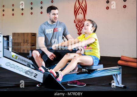 Ein junges Mädchen wurde eine Lektion auf einem Rudergerät in ein Fitnessstudio. Stockfoto