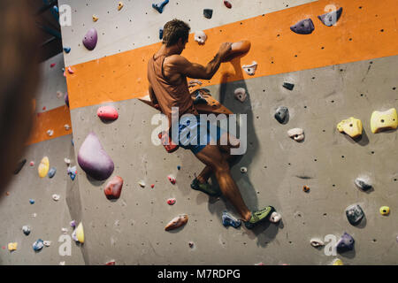 Man Bouldern in einer Kletterhalle. Kletterer üben Klettern in einer Kletterhalle. Stockfoto