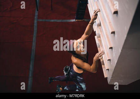 Frau üben Klettern auf einem Campus. Frau klettern auf einem Campus Brett an der Wand Kletterhalle. Stockfoto