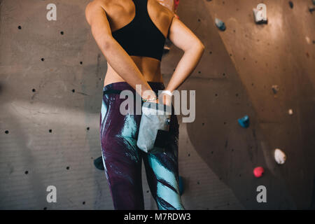 Ansicht der Rückseite Frau, bei der die Anwendung von Magnesium chalk Pulver auf die Hände aus der Tasche, um ihre Taille gebunden. 7/8 Schuß von Frau Anwendung greifen Pulver vor dem cli Stockfoto