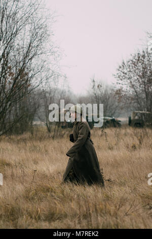 Gomel, Belarus - 26. November 2017: Eine rote Armee Soldat in einem Mantel entlang geht ein Feld von trockenem Gras Stockfoto
