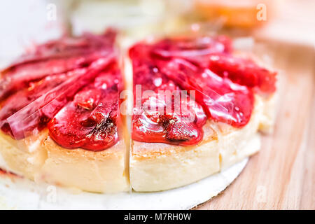 Nahaufnahme der Erdbeere gebackene Käsetorte Kuchen Schichten mit Sirup, Detail, Textur von roten Beeren auf Holztisch ganze Stockfoto