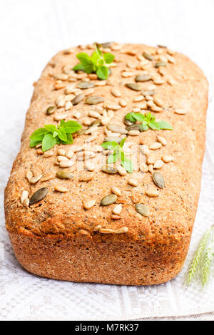 Hausgemachte ganze Roggen Brot mit Sonnenblumenkernen und griechischen Blätter Basilikum Stockfoto