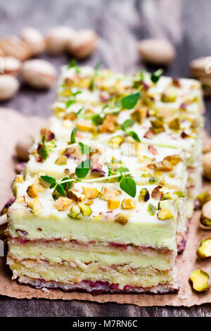Schichten von geschichteten Kuchen mit Pistazien auf hölzernen Hintergrund Stockfoto
