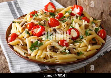 Traditionelle italienische vegetarische Penne Pasta mit Pilzen, Tomaten, Pfeffer closeup auf einem Teller. Horizontale Stockfoto