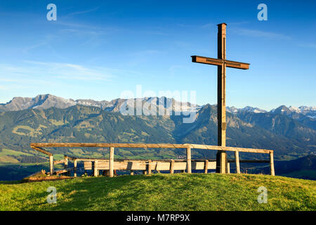 Hölzerne Gipfelkreuz mit erhabenen Blick auf einer Bergkette. Ofterschwanger Horn, Bayern, Deutschland. Stockfoto