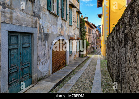 Schmale Straße mit Kopfsteinpflaster unter alten Häuser in der kleinen Stadt von Orta San Giulio in Piemont, Norditalien. Stockfoto