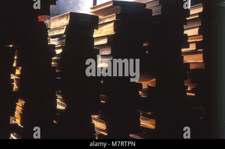 Stapel von Büchern auf dem Fensterbrett im Gegenlicht. Stockfoto