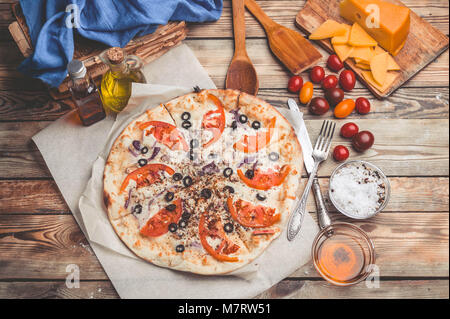 Pizza Margarita auf dünne Kruste. Die Zusammensetzung von Lebensmitteln auf einer hölzernen Hintergrund. Mediterrane Gerichte der traditionellen Küche. Einfach vintage Toning Stockfoto