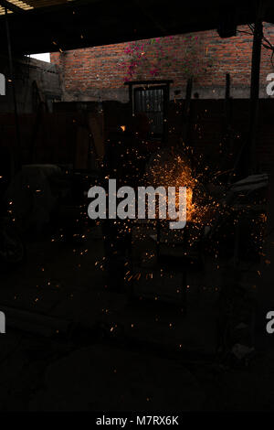 Arbeiter schneiden Eisenplatte mit Mahlwerk in alten Metallwerkstatt Stockfoto