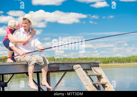 Fischer und seine Frau auf einem hölzernen Pier in der Nähe der See, ein Mann angeln Stockfoto
