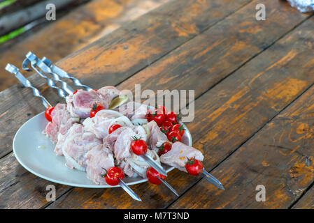 Auf einer hölzernen Tisch einen Teller mit raw Shish Kebab am Spieß Stockfoto