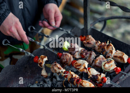 Männliche hand mit Shish Kebab Spieße auf dem Grill in der Nähe bis Stockfoto