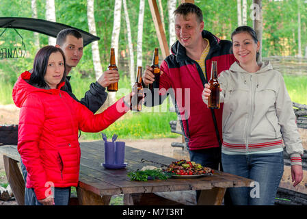 Freunde mit einem Grill und Bier auf die Natur im Pavillon Stockfoto