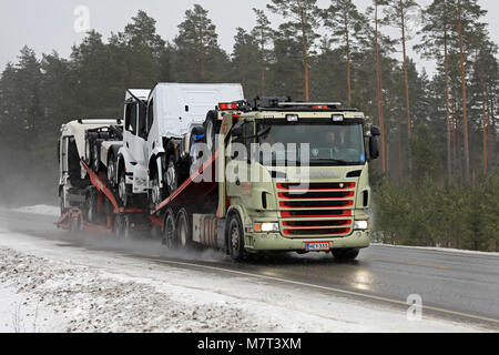 SALO, Finnland - 9. MÄRZ 2018: Scania Lkw Fahrzeug Träger von MotorTrans hols Drei neue schwere Lkw entlang nasse Straße in Schneefall im Süden Finnlands. Stockfoto