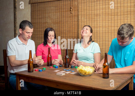 Junge Freunde Karten an einen Tisch drinnen sitzen, Bier trinken. Stockfoto
