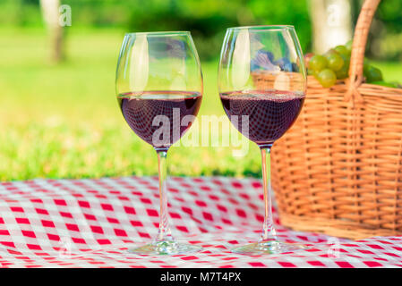 Close-up zwei Gläser Wein auf ein Picknick auf einem karierten Tischtuch auf dem Rasen Stockfoto