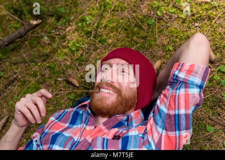 Close-up Portrait eines glücklichen Mann mit Bart auf dem Boden liegend im Wald Stockfoto