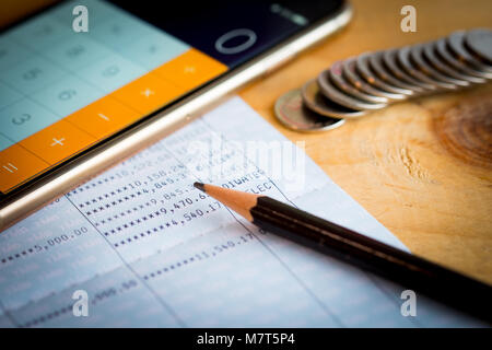 Sparkonto Sparbuch, Bleistift und Smartphone als Rechner auf hölzernen Tisch verwendet Stockfoto