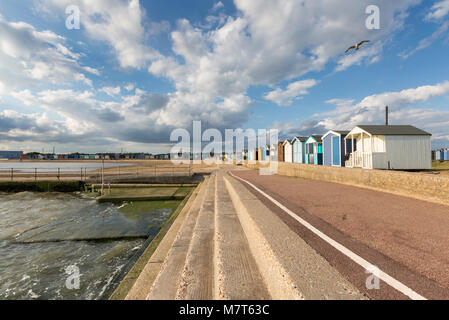 Helles Sonnenlicht und ein blauer Himmel über den Strandhütten und den Stufen am Gezeitenpool in Brightlingsea, Essex. Große Stratocumulus-Wolken sind sichtbar. Stockfoto
