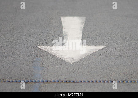 Weiße Farbe Pfeil Beschilderung nach hinten zeigend auf Asphalt Stockfoto
