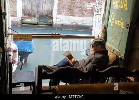 Venedig, Italien - 22. Januar 2018. Ein Tourist in Acqua Alta Libreria, die meisten berühmten benutzten Buchhandlung in Venedig. Stockfoto