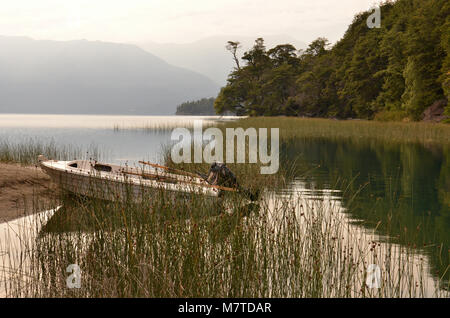 See Landschaft mit Boot zwischen Schilf auf der Vorderseite und nebligen Berge im Hintergrund. Stockfoto