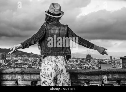 Perfekte Abend mit herrlichen Blick. Von hinten trendy Frau im langen Kleid und Strohhut im Stadtbild von Barcelona, Spanien gesehen Freude Stockfoto