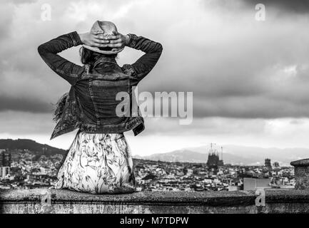 Perfekte Abend mit herrlichen Blick. Hinter jungen Touristen Frau im langen Kleid und Strohhut in der Stadt Panorama von Barcelona, Spanien Stockfoto