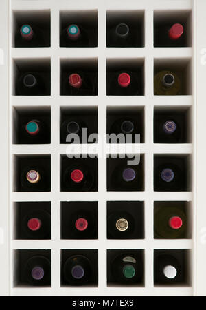 Kopf auf Foto von Holz- Integrierte Wine Rack voller Flaschen mit bunten Mützen. Retuschiert: Logos und Marken entfernt. Stockfoto