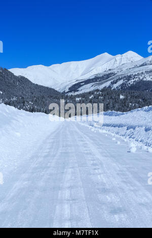 Straße durch tiefen Schnee im Winter gepflügt auf kleinschmidt flach unter den Bergen in der Nähe von Ovando, Montana Stockfoto