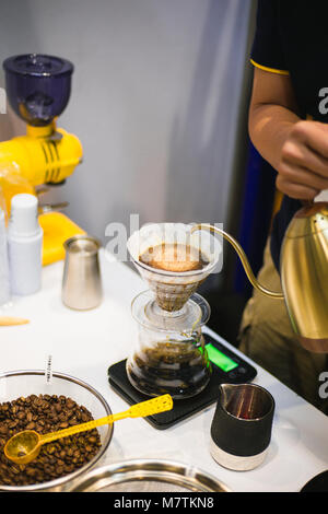 Strömenden heißen Wasser aus dem Wasserkocher Filter in Weiß Becher für Filterkaffee mit Zubehör für Kaffeemaschine Stockfoto