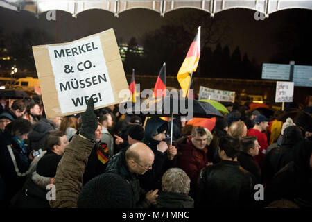 12 März 2018, Deutschland, Hamburg: die Teilnehmer der Protestbewegung Ereignis 'MErkel muss weg' (lit. Merkel hat zu gehen) am Dammtor Platz vor dem Bahnhof Dammtor demonstrieren. Einer der Teilnehmer hält ein Schild mit der Aufschrift 'MErkel & Co muessen weg!" (Lit. Merkel & Co zu bekommen). Mehrere hundert gegen Demonstranten versuchen, die Kundgebung zu stören. Foto: Christian Charisius/dpa Stockfoto