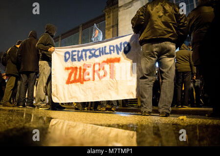 12 März 2018, Deutschland, Hamburg: die Teilnehmer der Protestbewegung Ereignis 'MErkel muss weg' (lit. Merkel hat zu gehen) am Dammtor Platz vor dem Bahnhof Dammtor demonstrieren. Zwei der Teilnehmer halten ein Banner Lesung "Deutschland Zuerst" (Lit. Deutschland zuerst). Mehrere hundert gegen Demonstranten versuchen, die Kundgebung zu stören. Foto: Christian Charisius/dpa Stockfoto