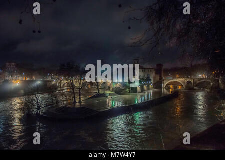 Tiberinsel auf dem Tiber in Rom bei Nacht mit bunten Reflexionen auf dem Wasser, Isola Tiberina Stockfoto
