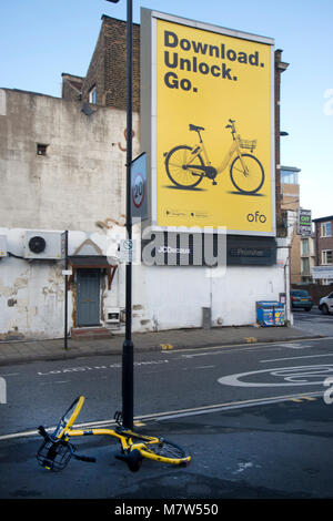 Mare Street, Hackney, London. Ein ofo Fahrrad blockiert den Bürgersteig gegenüber einer Anzeige für den Zyklus Regelung Stockfoto