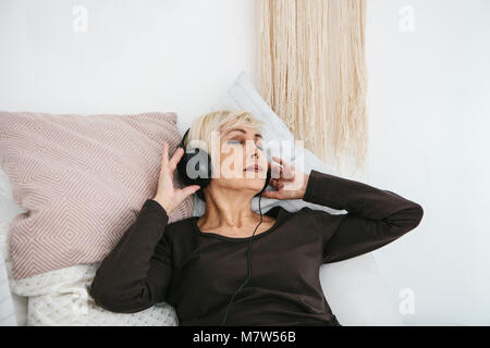 Positive ältere Frau Musik zu hören. Die ältere Generation und neue Technologien. Stockfoto