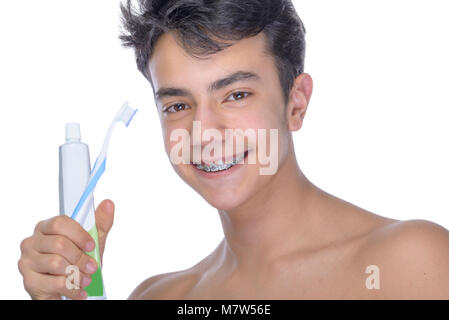 Cute Teenager mit weißem Hintergrund, das Tragen von Zahnspangen auf seine Zähne. Verwenden Zahnbürste und Zahnbürsten für die Reinigung. Stockfoto