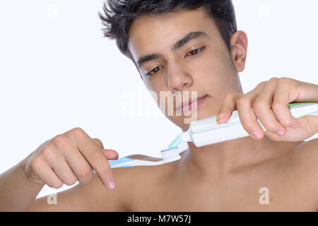 Cute Teenager mit weißem Hintergrund, das Tragen von Zahnspangen auf seine Zähne. Verwenden Zahnbürste und Zahnbürsten für die Reinigung. Stockfoto