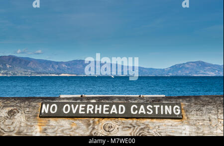 Holzschild auf Baumstamm Barriere sagen kein Overhead Casting am Pazifischen Ozean in Santa Barbara, Kalifornien, USA, mit Bergen in der Ferne Stockfoto