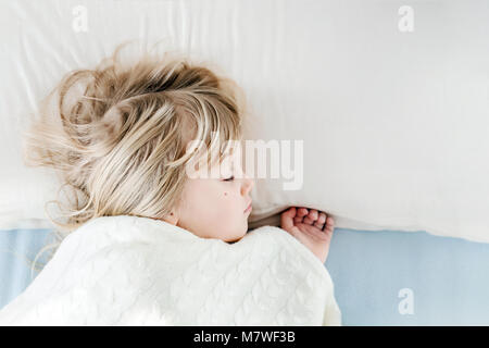 Kleine süße Mädchen schlafen auf Kissen im Bett. Kid bedeckt mit warmen weichen Garnen gestrickt Decke. Gesund schlafen tagsüber Konzept Stockfoto