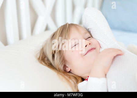 Kleine süße Mädchen Aufwachen im Bett. Kind stretching Arme. Lächelnd und nach gesunden Schlaf zufrieden. Happy sorglosen Kindheit Konzept. Guten Morgen Konzept Stockfoto