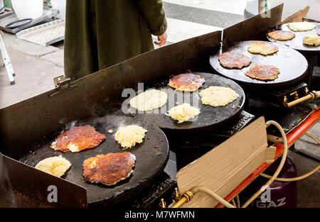 Les Gustalins stall und Galettes d'oignon Pomme de terre Fromage (Zwiebel Kartoffel Käse Pfannkuchen) Kochen auf den heißen Platten an der Marché Raspail in Par Stockfoto