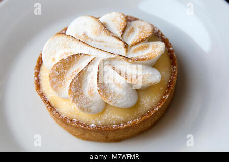 Ein Pariser Tarte au Citron (Lemon tart) mit Baiser wirbelt und Puderzucker Stockfoto