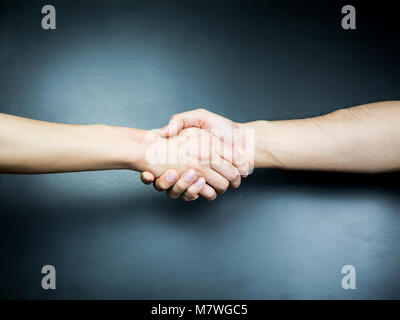 Mit beiden Händen Handshake auf schwarzem Hintergrund Stockfoto