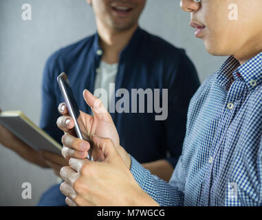 Zwei Männer sitzen zusammen mit Phone und Studium sprechen Stockfoto